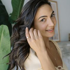 a woman is smiling and holding her hand up to her ear