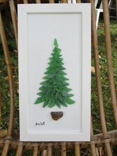 a small green christmas tree in a white frame on a wicker chair next to grass