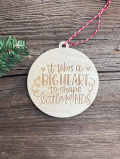 a wooden ornament that says it takes a big heart to shape little minds