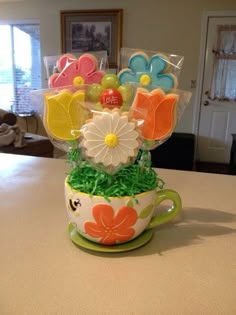 a cup filled with cookies and flowers on top of a kitchen counter next to a window