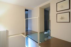 an empty room with a glass shelf and pictures on the wall, in front of a radiator