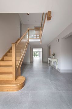 an empty hallway with stairs and table in the middle is seen from across the room