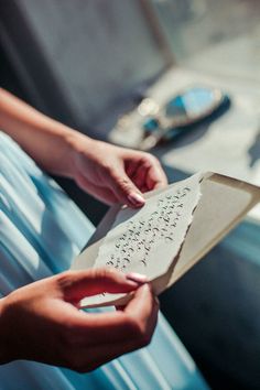 two hands holding a piece of paper with writing on it and another person's hand