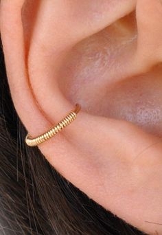 a close up of a person's ear with a gold ring on top of it