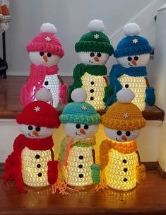 a group of knitted snowmen sitting on top of a stair case next to each other