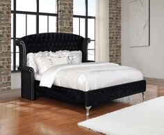 a bed with black velvet headboard and foot board in front of a brick wall