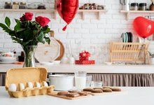 a vase with roses in it sitting on a table next to some cupcakes