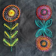 three different colored flowers on a black cloth with bead work in the shape of circles