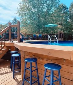 an above ground pool with two stools next to it and stairs leading up to the deck