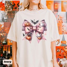 Get ready for Halloween in style with this adorable T-shirt featuring a pink bow graphic adorned with ghosts, bats, pumpkins, and stars! Perfect for those who love a cute and festive look, this tee combines Halloween/spooky vibes with a coquette aesthetic. Made with high-quality fabric for comfort and durability, it's a must-have for your spooky season wardrobe. Ideal for Halloween parties, casual outings, or as a unique gift.  💛 SIZING 💛 - This t-shirt comes in unisex sizing. - If you're look Pink Halloween T-shirt With Character Print, Pink Halloween Graphic Tee, Spooky Pink T-shirt For Halloween, Halloween Pink Cartoon Print Top, Pink Halloween Cartoon Print Top, Pink Cartoon Print Top For Halloween, Bow Shirts, Ghost Pumpkin, Trendy Halloween