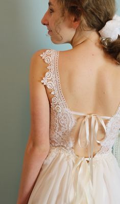 the back of a woman's wedding dress with a bow in her left hand