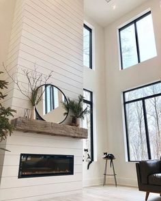 a living room filled with furniture and a fire place in front of two large windows