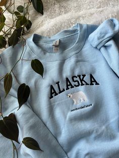 Soft and fleece-lined sweatshirt featuring Alaska in a varsity-like font featuring an adorable polar bear. This pullover Crewneck will keep you stylish and cool!  This sweatshirt is available in 8 colors:  ✨ Forest Green ✨ Military Green ✨ Black (words will be in white) ✨ Sand ✨ Indigo Blue ✨ Light Blue ✨ Navy (words will be in white) ✨ Ash Gray If there is a color you have in mind other than the ones available, send me a message and I can help! -Sweatshirt brand: Gildan -Sizes available: Adult Trendy College Sweatshirt With Embroidered Text, Cute Winter Sweatshirt For School, Sporty Winter Sweater With Letter Embroidery, Sporty Sweater With Letter Embroidery For Winter, Casual School Tops With Letter Embroidery, Casual Tops With Letter Embroidery For School, Casual Letter Embroidery Tops For School, Cute Winter Sweatshirt With Letter Print, School Fleece Crew Neck Sweatshirt