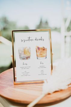 there is a sign that says signature drinks on the table next to a white feather