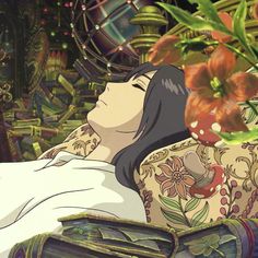 a woman laying on top of a bed in front of plants and flowers with her eyes closed