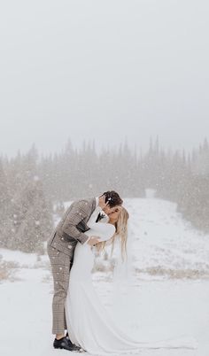 a bride and groom kissing in the snow