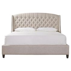 an upholstered bed with white linens and tufted headboard, made in the usa