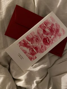 a red envelope with a handprint on it sitting on a white sheet covered bed