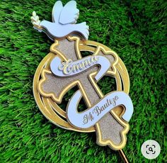 a lapel pin with an image of a cross and dove on it in the grass