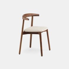 a wooden chair with a white upholstered seat and backrest, in front of a