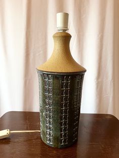 a brown vase sitting on top of a wooden table next to a toothbrush holder