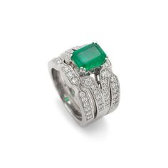 Gender: Ladies    Metal Type: 18K White Gold    Size: 5.5    Width: 2.85 mm    Ring measures approximately in width: 2.85 mm    Jacket measures in width: 8.50 mm    Weight: 15.69 grams    18K White Gold Diamond and Emerald Cocktail Ring with a soft-square shank. The ring is a size 5.5. The ring weighs a total of 15.69 grams. Engraved with "18K".    In Excellent Condition.    4-Prong Set in 18 Karat White Gold with:    One (1) natural, emerald-cut, step cut, emerald:    Species: Natural Beryl  Variety: Natural Emerald  Measurements: 8.66mm x 6.44mm x 3.83mm in depth.  Estimated Weight: 1.57 ct.  Cut Style: Crown Step Cut  Cut Style: Pavilion Step Cut  Color(s): Strongly Green  Clarity: Slightly Included (Type III)  Pavé set in 18 Karat White Gold with:    Fifty-four (54) round brilliant cut White Gold Emerald Cut Stackable Rings, Elegant Stackable Emerald Cut Rings, Stackable Emerald Cut White Gold Rings, Elegant Emerald Stackable Rings For Formal Occasions, Elegant Stackable Rings With Emerald Cut, Elegant Formal Emerald Stackable Rings, Luxury Gemstone Stackable Rings For Formal Occasions, Stackable White Gold Emerald Ring In Fine Jewelry Style, White Gold Stackable Emerald Ring Fine Jewelry