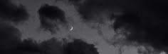 the moon is seen through some dark clouds