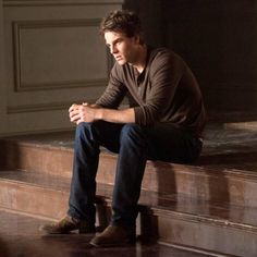 a young man sitting on top of a wooden bench next to a window sill