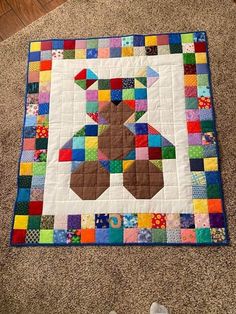 a person standing next to a quilted teddy bear on top of a carpet covered floor