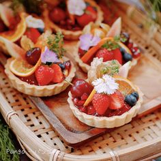 fruit tarts are arranged on a wooden tray