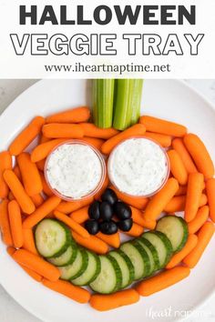 a white plate topped with carrots and cucumbers next to dip in the shape of a face