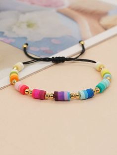 multicolored beaded bracelet with gold beads and black cord on an open book