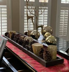 there is a tray with pine cones and candles on the table in front of it