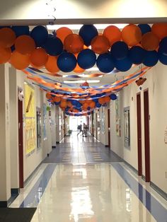 the hallway is decorated with orange, blue and white balloons that are hanging from the ceiling