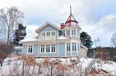 a blue and white house sitting on top of a snow covered hill