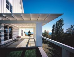 an outdoor covered patio with white siding and wood slats on the side of it