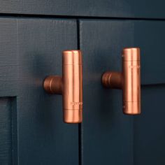 two copper handles on a blue cabinet