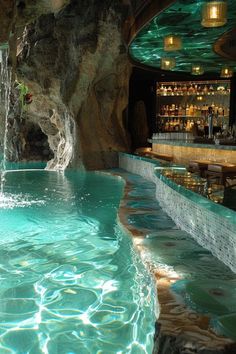 an indoor swimming pool with waterfall and bar in the background