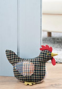 a black and white chicken sitting on top of a wooden floor next to a door