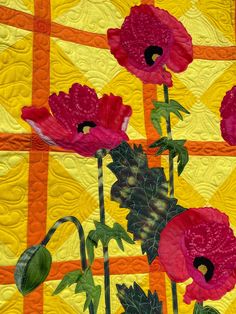 three red flowers are on a yellow and orange quilt