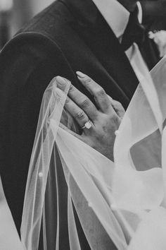 the bride and groom are holding each other's hands under their veiled veil