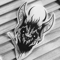 a black and white photo of a sticker with a demon on it's face