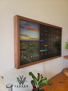 a wooden framed calendar hangs on the wall above a table with potted plants and other items