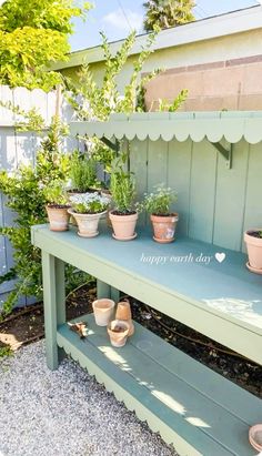 some potted plants are sitting on a green bench in front of a fenced area