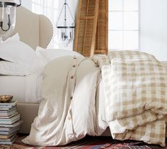 a bed with lots of pillows on top of it next to a pile of books