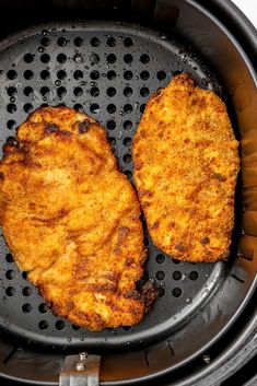 two fried chicken patties are in an air fryer with grates on the side