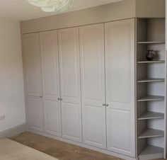 an empty room with white cupboards and shelves on the wall in front of it