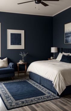 a bedroom with dark blue walls and white bedding, two couches and a rug on the floor