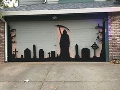 a man holding an umbrella standing in front of a garage door decorated with tombstones and crosses