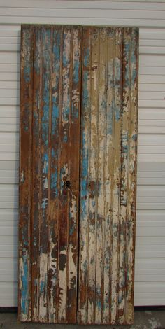 an old wooden door that has been painted blue and white with peeling paint on it